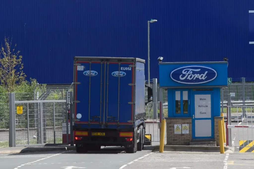 Ford-liveried articulated lorry leaving the main vehicle gate of a Ford manufacturing plant